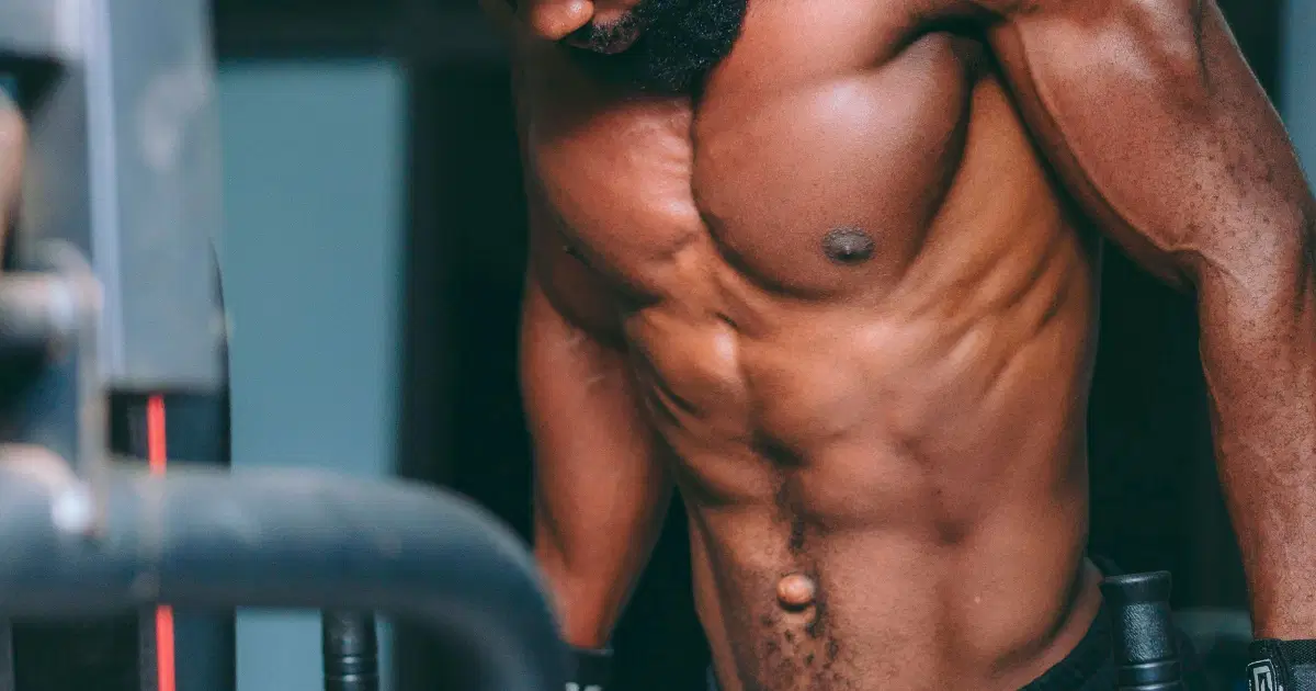 Close-up color photograph of a muscular torso in a moody warm interior